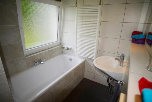 ein Badezimmer mit Badewanne und Waschbecken und einem Fenster in der Unterkunft Bungalow 21 - Nelderhut in Simpelveld