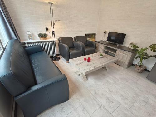 ein Wohnzimmer mit Sofas, einem Tisch und einem TV in der Unterkunft Bungalow 21 - Nelderhut in Simpelveld