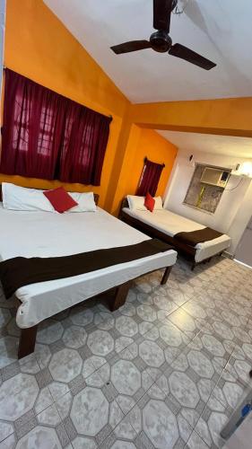 a bedroom with two beds and a ceiling fan at Marlin Beachway Rooms- Baga Beach in Baga