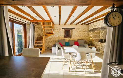una stanza con tavolo, sedie e orologio di Le fournil a Marcillac-la-Croisille