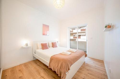 une chambre blanche avec un grand lit blanc et une fenêtre dans l'établissement GuestReady - Modern Comfort in Almada, à Almada