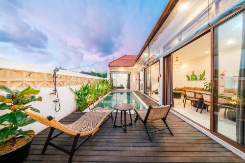 a deck with chairs and a table and a swimming pool at Villa Gadang in Kerobokan