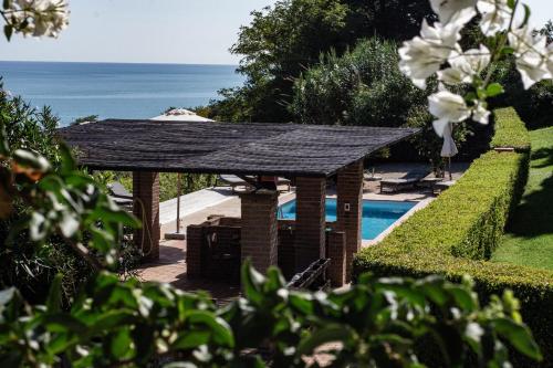 een paviljoen bij een zwembad met de oceaan op de achtergrond bij Casale Orgogliosa in San Vito Chietino