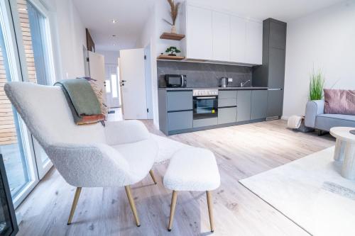 ein Wohnzimmer mit einem weißen Stuhl und einem Sofa in der Unterkunft Seeferienhaus am Süßen See 