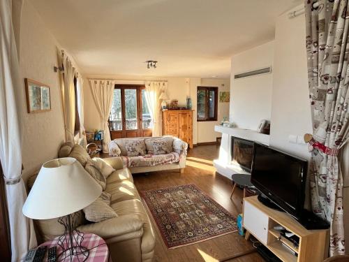 een woonkamer met een bank en een televisie bij Chalet Etienne in Jarrier