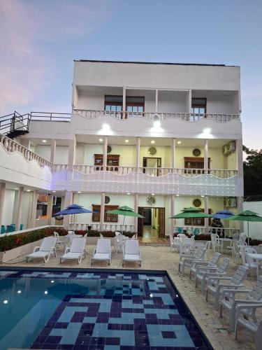 a hotel with a pool and chairs and a building at Hotel Santa Fe del Parque in Santa Fe de Antioquia