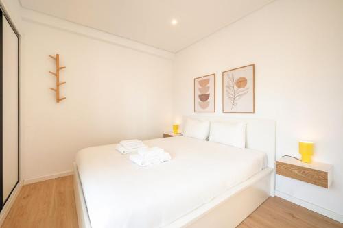 a white bedroom with a white bed with two lamps at GuestReady-Charming Coastal Getaway in Almada