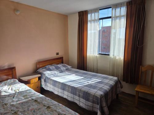 ein Hotelzimmer mit zwei Betten und einem Fenster in der Unterkunft Apartamento centrico en Puno in Puno