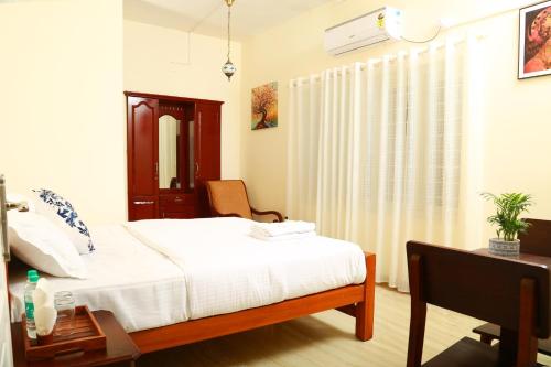 a bedroom with a bed and a desk and a window at Casa maryam in Fort Kochi