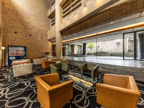 a lobby with chairs and tables in a building at APA Hotel Kanazawa Nomachi in Kanazawa