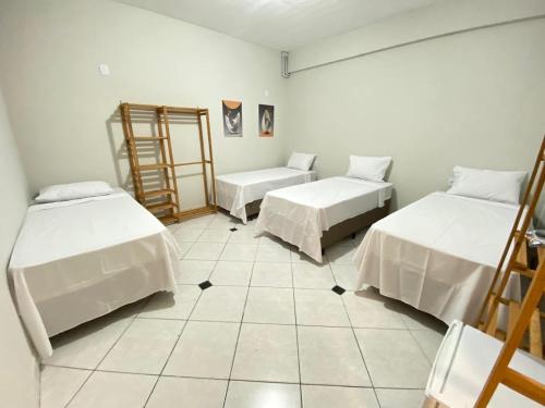 a room with two beds and a tiled floor at Pousada Âncora in Gravataí