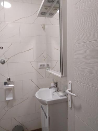 een witte badkamer met een wastafel en een spiegel bij Apartman,,Petko,, in Bajina Bašta
