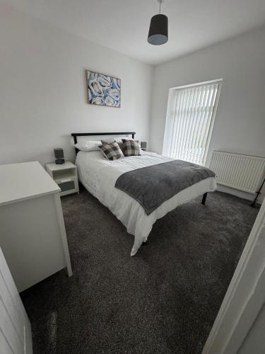 a white bedroom with a large bed and a window at Rosemary Cottage in Blaenavon