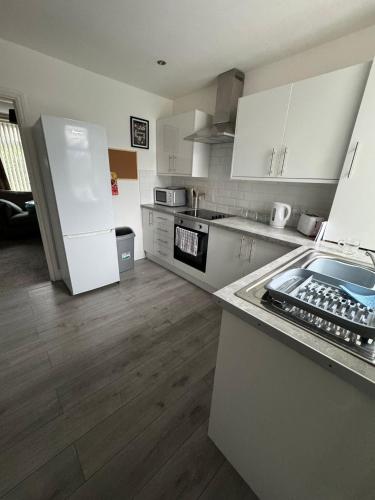 a kitchen with white cabinets and a white refrigerator at Rosemary Cottage in Blaenavon