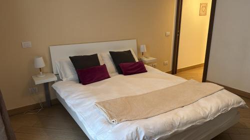 een groot wit bed met twee rode kussens erop bij Bon Bon Il Brofferio in Asti