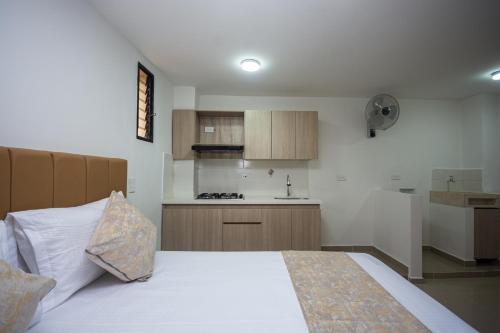 um quarto com uma cama branca e uma cozinha em Apartahotel Ces em Medellín