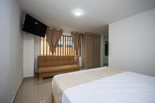 um quarto com uma cama, um sofá e uma janela em Apartahotel Ces em Medellín