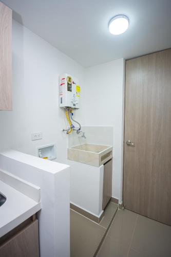 a white kitchen with a sink and a coffee maker at Apartahotel Ceo in Medellín