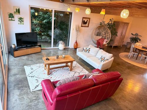 ein Wohnzimmer mit einem roten Sofa und einem Tisch in der Unterkunft La Verrière - maison écologique normande 