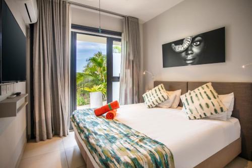een slaapkamer met een bed en een groot raam bij Luxury Beachfront Apt - Perfect for Beach Lovers in Rivière Noire