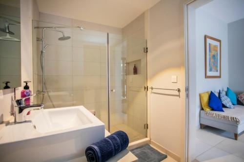 een badkamer met een wastafel en een glazen douche bij Luxury Beachfront Apt - Perfect for Beach Lovers in Rivière Noire