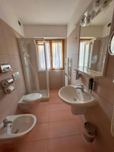 a bathroom with two sinks and a shower and a toilet at Hotel Alpe Bellaria in Candriai