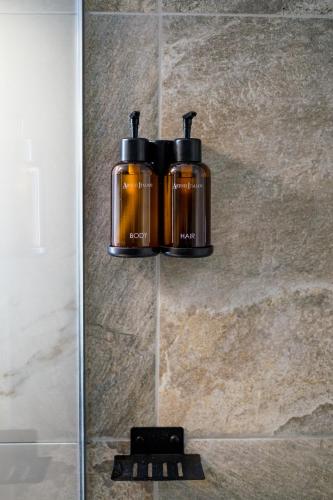 two bottles are hanging on a wall in a bathroom at Agnanti Apartment in Agrinio
