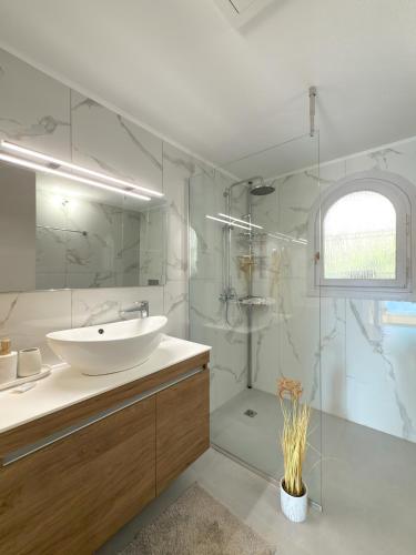 a white bathroom with a sink and a shower at Villa Kalami Look Out in Kalami