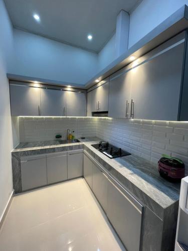 eine Küche mit weißen Schränken und einer Arbeitsplatte in der Unterkunft Cozy Homes BnB in Prampuan