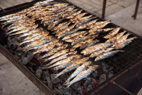 a bunch of fish cooking on a grill at B50 - Main Square Apartment in Lagos in Lagos