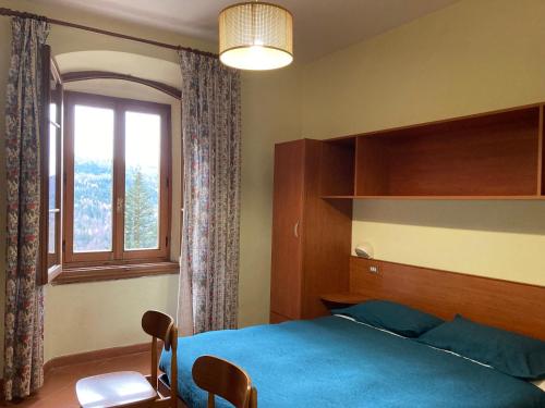 ein Schlafzimmer mit einem blauen Bett und einem Fenster in der Unterkunft B B Regina in Abetone