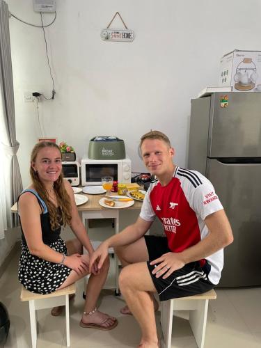 een man en een vrouw zitten op stoelen in een keuken bij Cozy Homes BnB in Prampuan