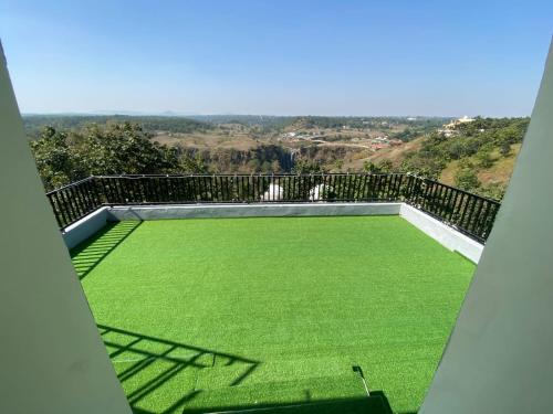 a balcony with a large yard of green grass at Staeg Dharashray Farm in Indore