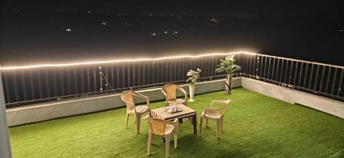 a patio with chairs and a table on a balcony at night at Staeg Dharashray Farm in Indore