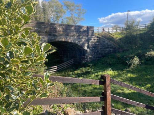 Un puente de piedra con una valla delante. en West Coast Whistlestop, en Ochiltree
