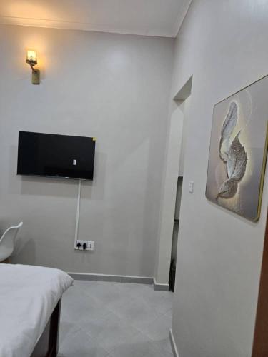 een witte kamer met een tv aan de muur bij Kibs apartments in Dodoma