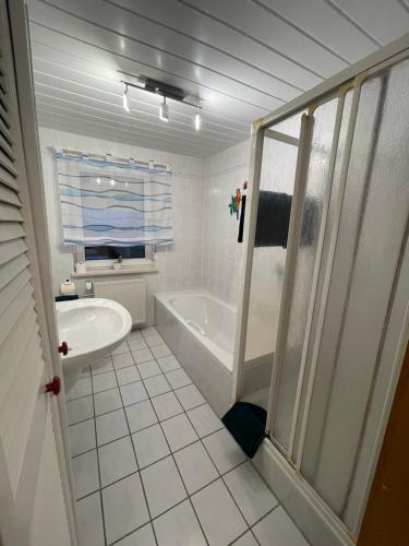 Un baño blanco con bañera y ducha. en Ferienwohnung Matthias Lang, en Rugendorf