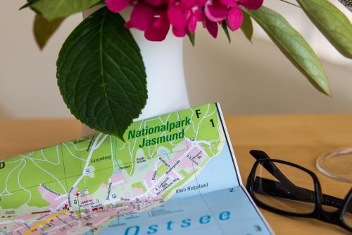 a map on a table next to a vase with flowers at Ostseeblick Sassnitz in Sassnitz