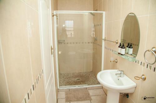 a bathroom with a shower and a toilet and a sink at Emmanuel Guesthouse in eMalahleni
