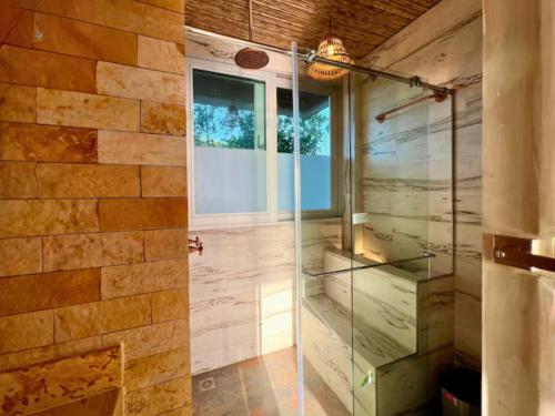 a glass shower in a bathroom with a stone wall at Casa Luna Laguna Beach in Tolú