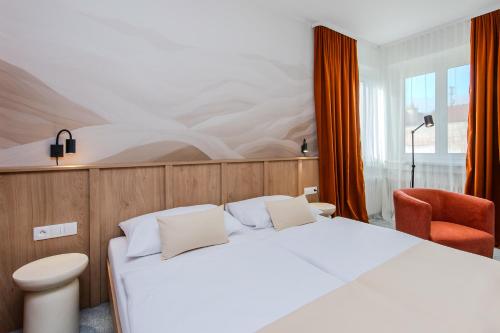 una camera da letto con un letto bianco e una sedia rossa di Le Petit a Bratislava