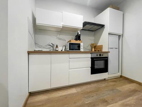 a kitchen with white cabinets and a microwave at appartement t2 la doutre 2-4 personnes in Angers