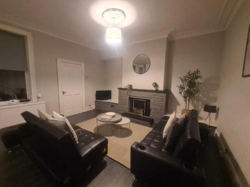 a living room with two black couches and a fireplace at Town Centre Apartments in Westoe
