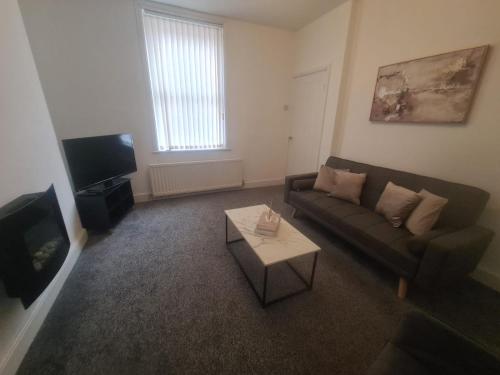 ein Wohnzimmer mit einer Couch und einem Couchtisch in der Unterkunft Cosy 3 bed House South Shields in Jarrow
