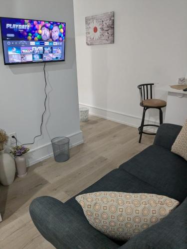 a living room with a couch and a tv on the wall at Brand New Private Unit with Parking, Steps to TTC, 15 Minutes to Downtown in Toronto