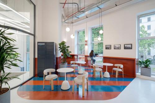 Um saguão com mesas e cadeiras e uma mulher ao fundo. em aparto Milan Ripamonti em Milão