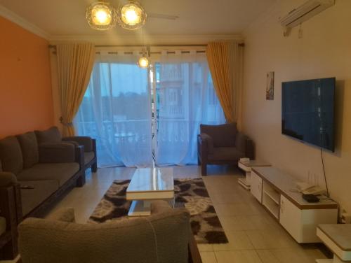 Una sala de estar con un sofá y un televisor. en Royal D8, en Mombasa