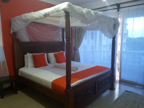 Un dormitorio con una cama con dosel con almohadas de color naranja y naranja. en Royal D8, en Mombasa