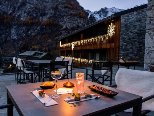 a table with wine glasses and food on a patio at Grand Hotel Courmayeur Mont Blanc, by R Collection Hotels in Courmayeur