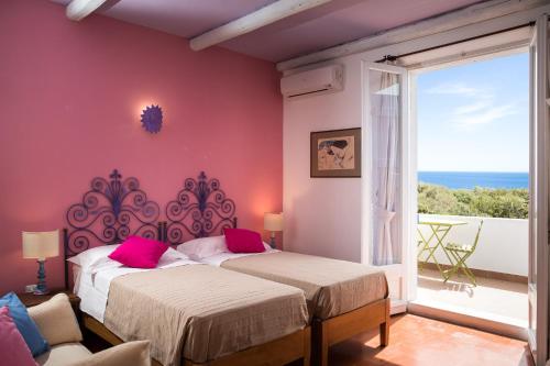 a bedroom with two beds and a large window at PALMASERA CHARMING - Rooms & Suites in Cala Gonone